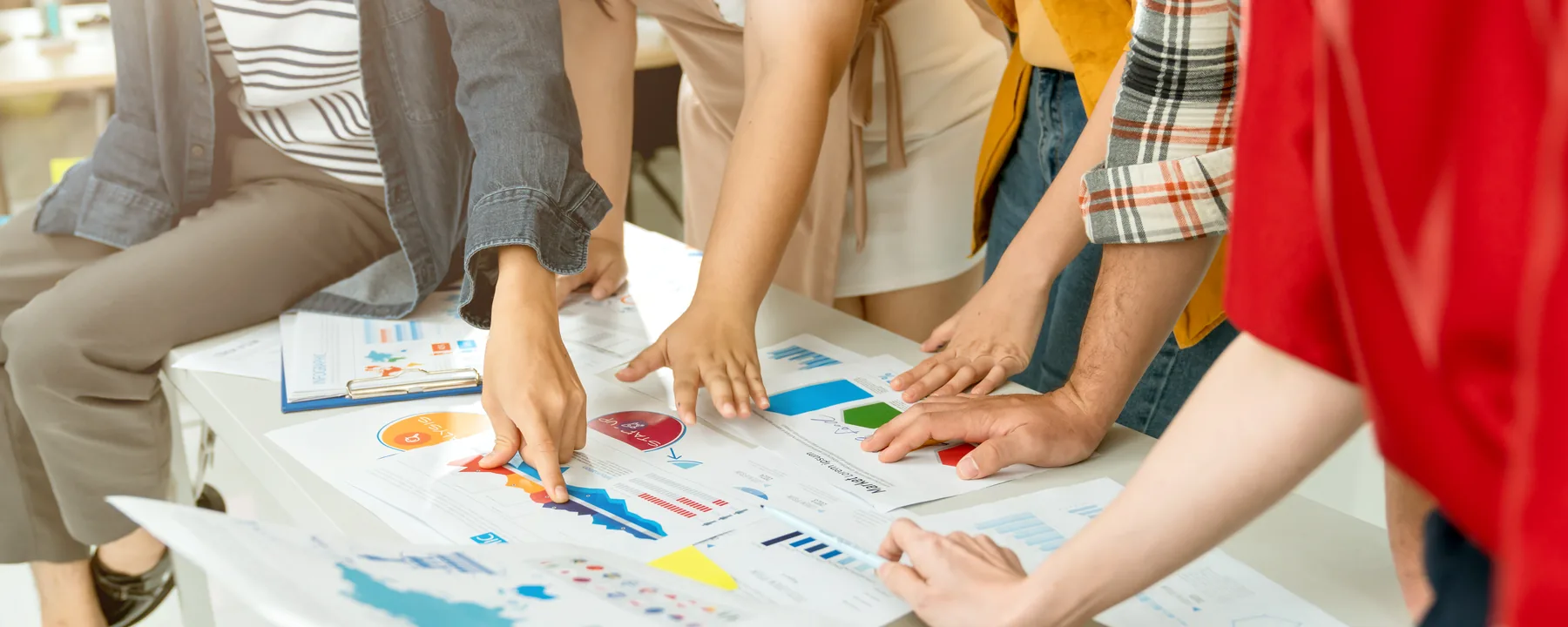 Nhóm bạn trẻ cùng đứng quanh bàn, phân tích các bản biểu đồ và kế hoạch marketing
