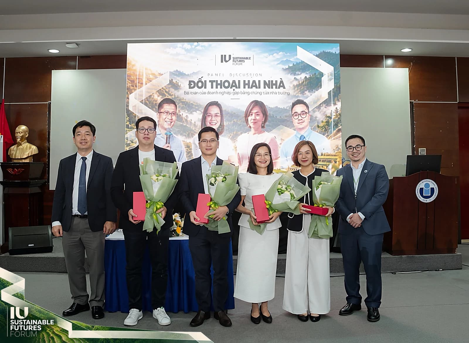 Các diễn giả phiên đối thoại cầm hoa chụp ảnh cùng ban tổ chức trước màn hình Đối thoại hai nhà