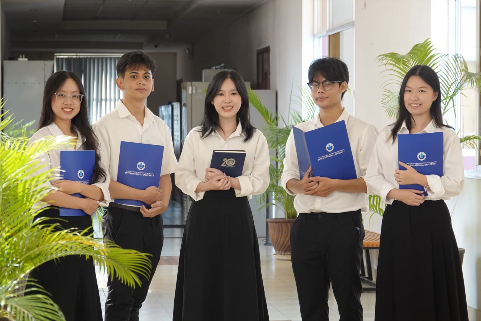 Năm sinh viên Trường Đại học Quốc tế IU cầm bìa hồ sơ có logo trường