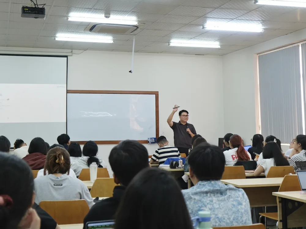 Anh Dũng Vũ trình bày trước màn chiếu, sinh viên ngồi kín các dãy bàn