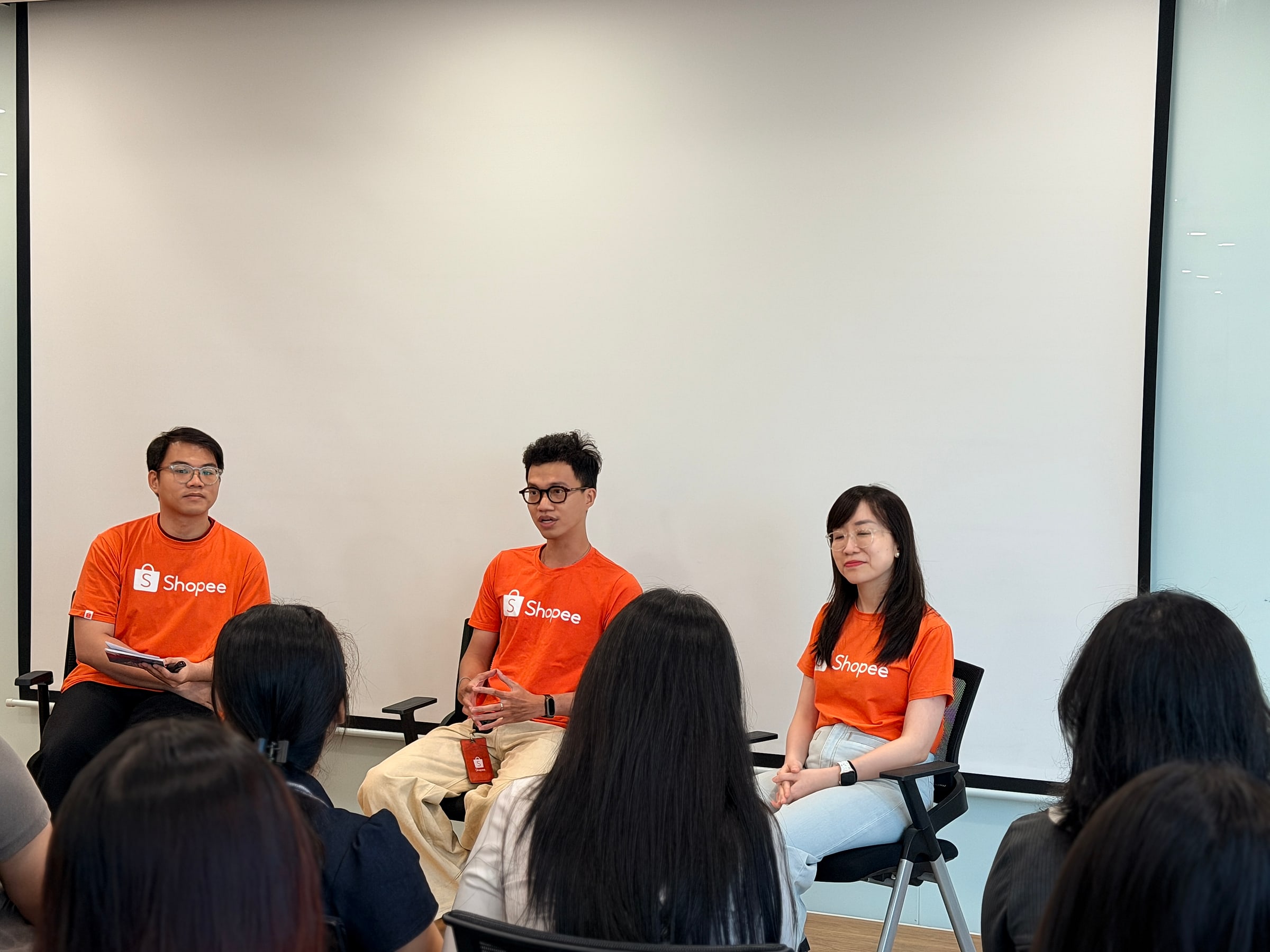 Ba nhân sự Shopee mặc áo cam ngồi trò chuyện cùng sinh viên IU